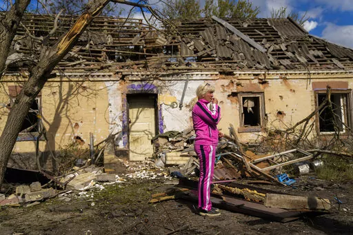 Iryna Martsyniuk, 50, stands next to her house, heavily damaged after a Russian bombing in Velyka Kostromka village, Ukraine, Thursday, May 19, 2022. Martsyniuk and her three young children were at home when the attack occurred in the village, a few kilometres from the front lines, but they all survived unharmed. (AP Photo/Francisco Seco)