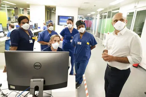 Britain's Health Secretary Sajid Javid, right, meets staff in a COVID-19 Intensive Care Unit during a visit to Kings College Hospital in London, Friday Jan. 7, 2022. (Stefan Rousseau/PA via AP)
