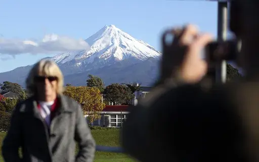 A man takes a picture of his wife with Mount Taranaki, also known as Mount Egmont, in the background in New Plymouth, New Zealand, Sept. 26, 2011. (AP Photo/Dita Alangkara, File)