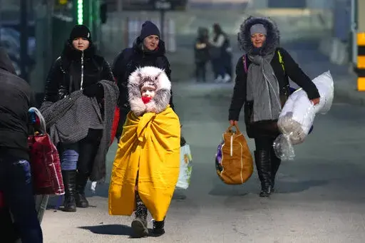 People fleeing the conflict in neighboring Ukraine cross the border in Przemysl, Poland, Sunday, Feb. 27, 2022. Street fighting broke out in Ukraine's second-largest city Sunday and Russian troops put increasing pressure on strategic ports in the country's south following a wave of attacks on airfields and fuel facilities elsewhere that appeared to mark a new phase of Russia's invasion. (AP Photo/Petr David Josek)