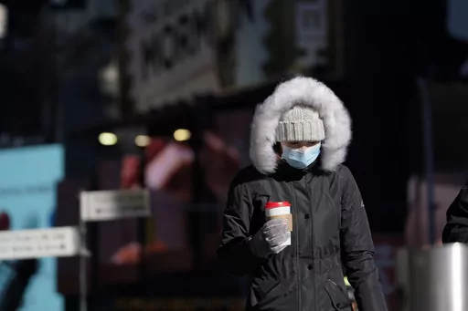 A pedestrian wears a heavy coat against the cold in New York, Tuesday, Jan. 11, 2022. January can be the worst month for respiratory illnesses and vaccination rates are low. When relatives, friends and co-workers are coming down with coughs, nasal congestion, fatigue and fever, keeping viruses at bay means thorough hand-washing, good ventilation and wearing a mask in crowded areas. (AP Photo/Seth Wenig, File)