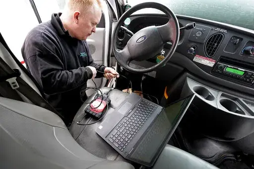 Brian Hohmann, mechanic and owner of Accurate Automotive, in Burlington, Mass., attaches a diagnostics scan tool, center left, to a vehicle and a laptop computer, below, Tuesday, Feb. 1, 2022, in Burlington, Mass. The diagnostics scan tool sends information from the vehicle's computer to the laptop so a mechanic can view information about the vehicle's performance. Hohmann said most independent shops are perfectly capable of competing with dealerships on both repair skills and price as long as t