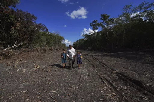 Omar Hernandez walks with his daughters on land he sold for the construction of a section of the Maya Train, near the Calakmul Biosphere Reserve in the Yucatan Peninsula of Mexico on Wednesday, Jan. 11, 2023. Hernandez hopes to sell organic honey he produces to tourists. He had to relocate his hives though, worried the heavy machinery would scare them away. (AP Photo/Marco Ugarte)
