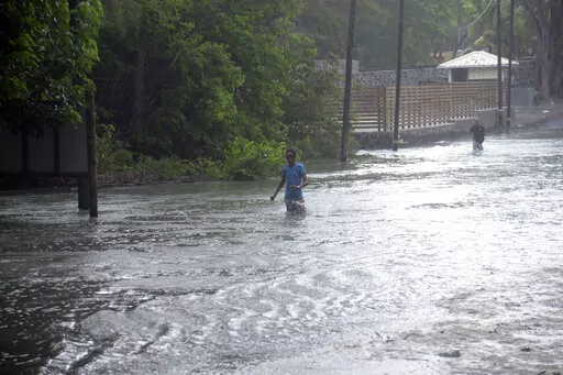 A man walks through a flooded road in the coast of the Indian Ocean Island of Mauritius Monday Feb. 20, 2023. Forecasts say Tropical Cyclone Freddy is increasing in intensity and is expected to pass north of the Indian Ocean island nation of Mauritius and make landfall in central Madagascar Tuesday evening.It's feared that up to 2.2 million people, mostly in Madagascar, will be impacted by storm surges and flooding, according to the Global Disaster Alert and Coordination System.(AP Photo/L'expre
