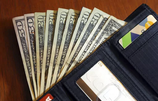 In this June 15, 2018, file photo, cash is fanned out from a wallet in North Andover, Mass.  Mapping out planned expenses like vacations, holiday gifts and membership renewals in advance gives you time to save in smaller chunks. “Sinking” your funds into buckets created for each savings goal is one way to avoid feeling overwhelmed as the deadline approaches. (AP Photo/Elise Amendola, File)
