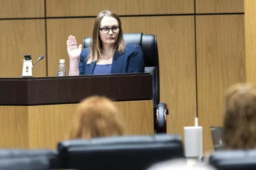 Cobb County teacher Katie Rinderle is sworn in to testify during a hearing at the Cobb County Board of Education in Marietta, Ga., Aug. 10, 2023. The firing of Rinderle, a Georgia teacher who read a book on gender fluidity to her fifth grade class, was upheld Thursday, Feb. 22, 2024, by the Georgia Board of Education. (Arvin Temkar/Atlanta Journal-Constitution via AP, File)