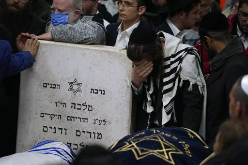Mourners gather around the bodies of Israeli couple Eli Mizrahi and his wife, Natalie, victims of a shooting attack Friday in east Jerusalem, during their funeral at the cemetery in Beit Shemesh, Israel, early Sunday, Jan. 29, 2023. On Friday, a Palestinian gunman opened fire outside an east Jerusalem synagogue, killing the couple and another five people, including a 70-year-old woman, and wounding three others before he was shot and killed by police, officials say. It was the deadliest attack o