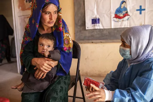 A Save the Children nutrition counsellor, right, explains to Nelab, 22, how to feed her 11-month-old daughter, Parsto, with therapeutic food, which is used to treat severe acute malnutrition, in Sar-e-Pul province of Afghanistan, Thursday, Sept. 29, 2022. (Save the Children via AP, File)