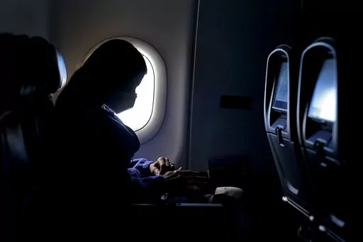 In this Wednesday, Feb. 3, 2021, file photo, a passenger wears a face mask she travels on a flight from Hartsfield-Jackson International Airport in Atlanta. In a lawsuit filed Tuesday, March 29, 2022, Florida and 20 other states are suing to halt the federal government's pandemic requirement that people wear masks on planes, trains and other public transport. (AP Photo/Charlie Riedel, File)