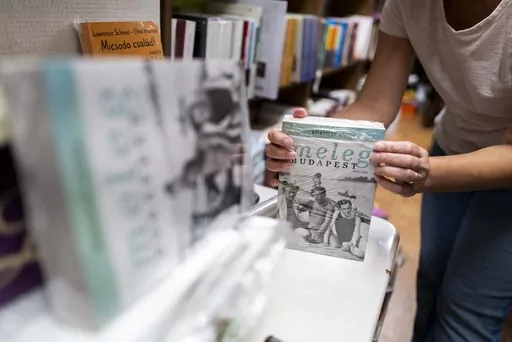 An employee of a bookstore wraps a book featuring LGBTQ+ content in closed packaging to comply with a contentious law on homosexuality in media, on Wednesday, July 26, 2023 in Budapest, Hungary. Booksellers in Hungary must decide whether to comply with a law requiring books that depict homosexuality to be placed in closed packaging on their shelves. Some bookstores have already received hefty fines from the right-wing government for failing to do so, while others have opted to abide by the legis