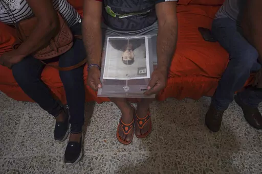 Salvador Morales holds a folder containing a photo of his disappeared son Alan Morales, during a meeting of the Milynali Network, a collective of families that aid in searches of disappeared relatives, in Ciudad Mante, Mexico, Monday, Jan. 31, 2022. Morales said his son Alan was coming back from picking oranges with his own 7-year-old son when he disappeared with four other people in October. (AP Photo/Marco Ugarte)