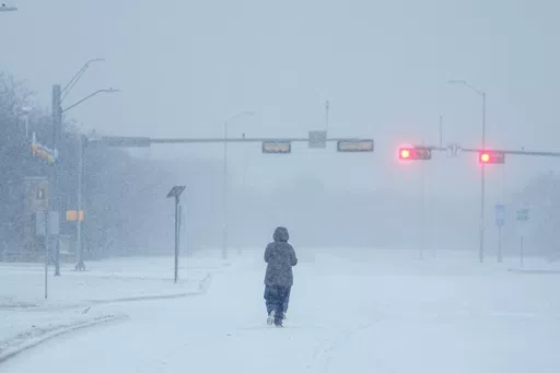 A jogger trots on a snow-covered road during a winter storm, Jan. 15, 2024, in Grand Prairie, Texas. Winter weather brings various hazards that people have to contend with to keep warm and safe. These dangers can include carbon monoxide poisoning, hypothermia and frozen pipes that can burst and make homes unlivable. Public safety officials and experts say there are multiple ways people can prepare themselves to avoid these hazards and keep themselves safe. (AP Photo/Julio Cortez, file)