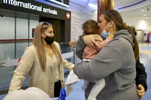 Families embrace after a flight from Los Angeles arrived at Auckland International Airport as New Zealand's border opened for visa-waiver countries Monday, May 2, 2022. New Zealand welcomed tourists from the U.S., Canada, Britain, Japan and more than 50 other countries for the first time in more than two years as it dropped most of its remaining pandemic border restrictions. (Jed Bradley/New Zealand Herald via AP)