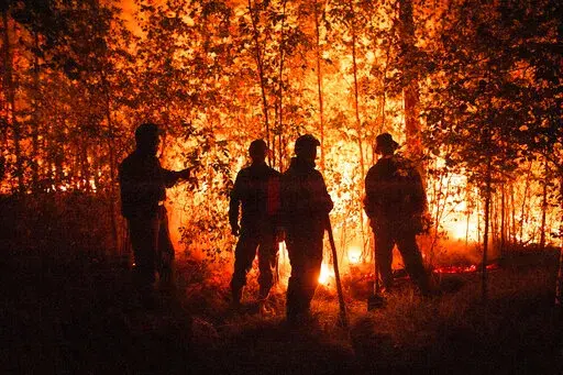 FILE -Firefighters work at the scene of forest fire near Kyuyorelyakh village at Gorny Ulus area, west of Yakutsk, in Russia Thursday, Aug. 5, 2021. A warming planet and land use changes mean more wildfires will scorch large parts of the globe in coming decades. That's according to a UN report released Wednesday, Feb. 23, 2022 that says many governments are ill-prepared to address the problem.  (AP Photo/Ivan Nikiforov, File)