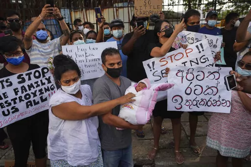 A Sri Lankan couple with their infant join an anti government protest during a curfew in Colombo, Sri Lanka, Sunday, April 3, 2022. Opposition lawmakers and people angered by the government's handling of Sri Lanka's worst economic crisis on Sunday marched to denounce the president's move to impose a nationwide curfew and state of emergency, as protests over food and fuel shortages swelled.  (AP Photo/Eranga Jayawardena)