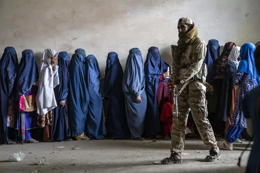 A Taliban fighter stands guard as women wait to receive food rations distributed by a humanitarian aid group, in Kabul, Afghanistan, Tuesday, May 23, 2023. Two top international rights groups on Friday, May 26, slammed the severe restrictions imposed on women and girls by the Taliban in Afghanistan, saying they amount to the “crime against humanity of gender persecution.” (AP Photo/Ebrahim Noroozi, File)