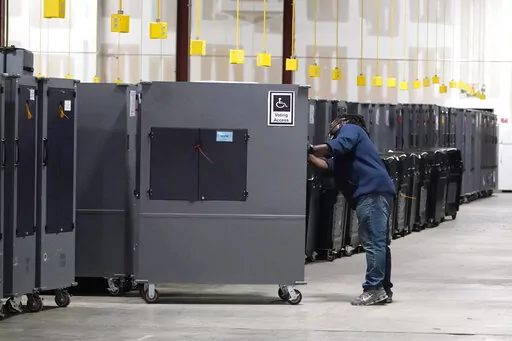 A worker returns voting machines to storage at the Fulton County Election preparation Center on Nov. 4, 2020 in Atlanta, Ga. The list of security breaches at local election offices since the 2020 election keeps growing, with investigations ongoing in at least three states, Colorado, Georgia and Michigan. Security experts say the breaches by themselves have not necessarily increased threats to the November elections, but say they increase the possibility that rogue election workers could access e