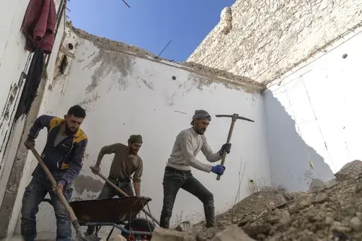 People clear the rubble inside a home that was damaged and looted, in Maarat al-Numan, on the outskirts of Idlib, Syria, Wednesday, Jan. 15, 2025. (AP Photo/Mosa'ab Elshamy)
