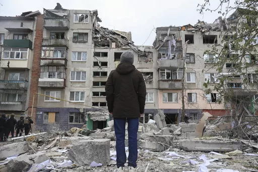 A local resident looks at his home, damaged by a Russian rocket attack in Sloviansk, Donetsk region, Ukraine, Friday, Apr. 14, 2023. The death toll from Russian missile strikes on eastern Ukraine's city of Sloviansk rose to 11 Saturday as rescue crews tried to reach people trapped in the rubble of an apartment building, Ukrainian authorities said. (Roman Chop via AP)