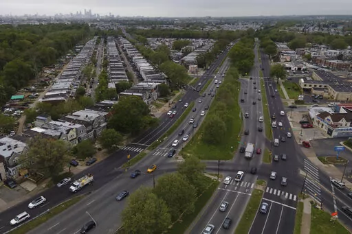 The Philadelphia skyline, top, is seen at a distance as vehicular traffic flows along Roosevelt Boulevard at the intersection with Whitaker Avenue, Thursday, May 12, 2022, in Philadelphia. Roosevelt Boulevard is an almost 14-mile maze of chaotic traffic patterns that passes through some of the city's most diverse neighborhoods and Census tracts with the highest poverty rates. Driving can be dangerous with cars traversing between inner and outer lanes, but biking or walking on the boulevard can b