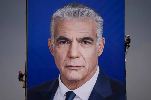 Workers hang an election campaign billboard showing Israeli Prime Minister and the head of the Yesh Atid party Yair Lapid, in Ramat Hasharon, Israel, Sunday, Oct. 23, 2022. Israel is heading into its fifth election in under four years on Nov. 1. (AP Photo/Oded Balilty, File)