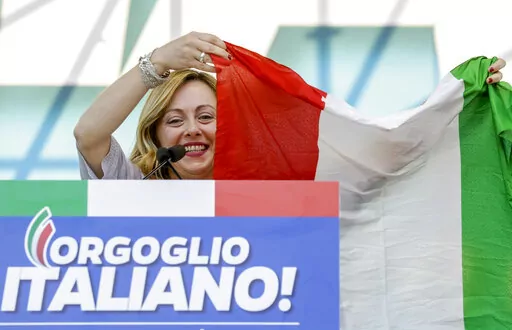 FILE — Giorgia Meloni holds an Italian flag as she addresses a rally in Rome, Saturday, Oct. 19, 2019. With God, homeland and "natural" family prominent in her political manifesto, Giorgia Meloni, whose Fratelli d'Italia (Brothers of Italy) party with neo-fascist roots has been fast rising in popularity in view of the upcoming Sept. 25 elections for Parliament, is positioning herself to become Italy's first far-right premier and the first woman to hold that office. (AP Photo/Andrew Medichini)
