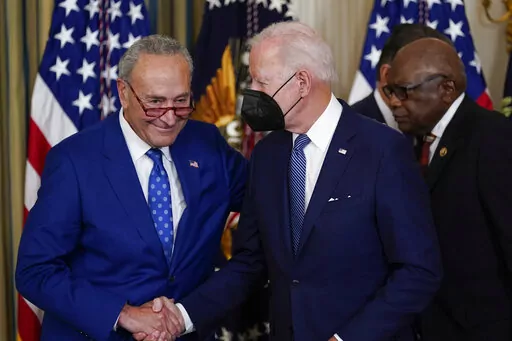 President Joe Biden shakes hands with Senate Majority Leader Chuck Schumer of N.Y., after signing the Democrats' landmark climate change and health care bill in the State Dining Room of the White House in Washington, Tuesday, Aug. 16, 2022. At back right is Rep. James Clyburn, D-S.C. (AP Photo/Susan Walsh)