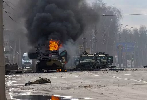 A Russian armored personnel carrier burns amid damaged and abandoned light utility vehicles after fighting in Kharkiv, the country's second-largest city in Ukraine, Feb. 27, 2022. Three months after it invaded Ukraine hoping to overtake the country in a blitz, Russia has bogged down in what increasingly looks like a war of attrition with no end in sight. (AP Photo/Marienko Andrew, File)