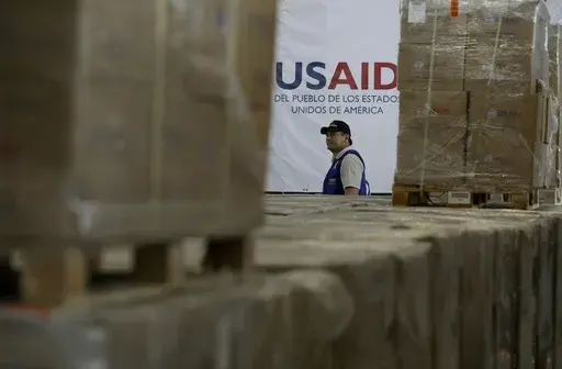 A man walks past boxes of USAID humanitarian aid at a warehouse at the Tienditas International Bridge on the outskirts of Cucuta, Colombia, Feb. 21, 2019, on the border with Venezuela. (AP Photo/Fernando Vergara, File)