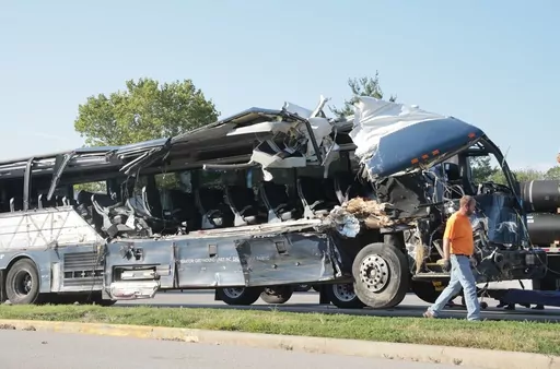 A worker helps clear the wreckage of a Greyhound bus that collided with tractor-trailers on the exit ramp to a rest area on westbound Interstate 70 in Highland, Ill., on Wednesday, July 12, 2023. (Christian Gooden/St. Louis Post-Dispatch via AP)