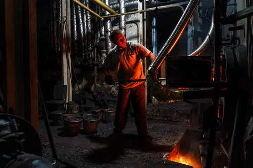 Dmytro, one of three men working a 12-hour night shift, loads coal into a boiler at a bakery in Kostiantynivka, Donetsk region, eastern Ukraine, Monday, Aug. 15, 2022. The bakery has remained open despite many challenges. In April it lost its gas supply, but the ovens were reconfigured to run on coal, a system which hadn't been used at this plant since World War II. It's one of two large-scale bakeries left in operation in the Ukrainian-held part of the Donetsk region, most of which is under Rus