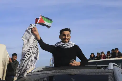A man waves a Palestinian flag as he returns home to Rafah, after a ceasefire deal between Israel and Hamas went into effect, in Rafah, Gaza Strip, Jan. 19, 2025. (AP Photo/Mariam Dagga, File)