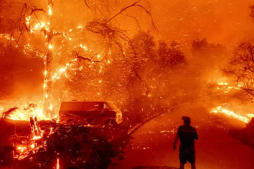 Bruce McDougal watches embers fly over his property as the Bond Fire burns through the Silverado community in Orange County, Calif., on Dec. 3, 2020. New research shows climate misinformation has been flourishing on Twitter since Elon Musk purchased the platform in 2022. (AP Photo/Noah Berger, File)