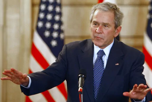 U.S. President George W. Bush, reacts, after shoes were thrown at him, by a correspondent, during a joint press conference with Iraq Prime Minister Nouri al-Maliki, not seen, in Baghdad, Iraq, Dec. 14, 2008.  Bush is facing criticism after mistakenly describing the invasion of Iraq — which he led as commander in chief — as “brutal” and “wholly unjustified,” before correcting himself to say he meant to refer to Russia’s invasion of Ukraine. He added, “Iraq, too — anyway.” The 