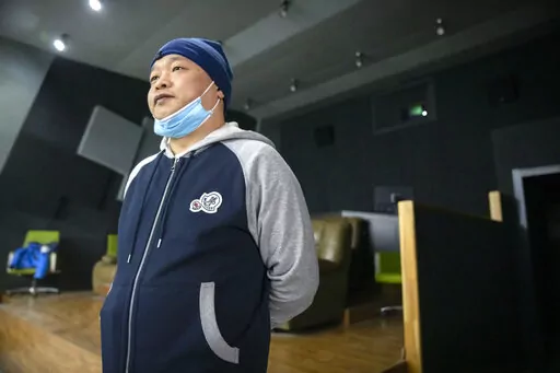 Lan Bo, director of the documentary film "Wuhan, I Am Here," stands in a screening room before a viewing of his movie in Beijing, Saturday, Jan. 15, 2022. The homeless, the sick, the elderly: For people who fell through the cracks of the official system, the then-unprecedented decision to isolate the central Chinese city of Wuhan and its 13 million people was a matter of life or death. Director Lan Bo hopes to sound the alarm with a documentary about volunteers who helped neighbors get food and 