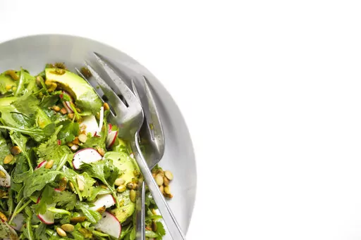 This image released by Milk Street shows a recipe for Arugula and Avocado Salad with Jalapeño Vinaigrette. (Milk Street via AP)