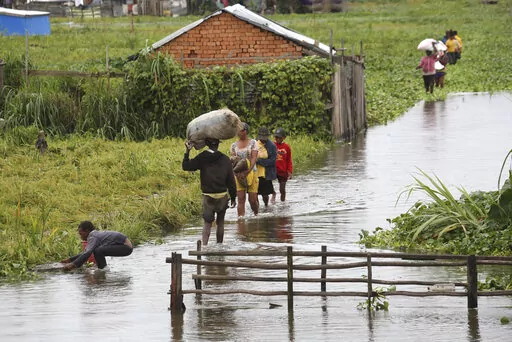 Residents wade through floodwater around their homes after heavy rain in Antananarivo, Madagascar, Jan. 19, 2022, killed at least 10 people. African officials outlined their priorities for the upcoming U.N. climate summit, including a push to make heavily polluting rich nations compensate poor countries for the environmental damage done to them. The continent will also focus on how countries can adapt to global warming and how the continent can best halt further climate-related disasters. (AP Ph