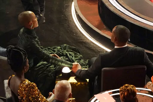 Jada Pinkett Smith, left, and Will Smith hold hands in the audience at the Oscars in Los Angeles on March 27, 2022. Will Smith stunned the audience of the 94th Academy Awards ceremony on Sunday when he walked onstage and slapped comedian Chris Rock over a joke the presenter made about his wife. Pinkett Smith turned her husband’s Oscar-night blowup into a teachable moment on “Red Table Talk,” her Facebook Watch show on June 1. (AP Photo/Chris Pizzello, File)