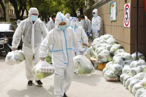In this photo released by Xinhua News Agency, volunteers carry daily necessities for residents in Fengxian District in eastern China's Shanghai city on Monday, March 28, 2022. China began its most extensive coronavirus lockdown in two years Monday to conduct mass testing and control a growing outbreak in Shanghai as questions are raised about the economic toll of the nation's "zero-COVID" strategy. (Wang Yanting/Xinhua via AP)