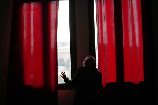 Pakistani-born Iram Aslam, 29, peeks through the window of a local social activities center in Guastalla, northern Italy, Saturday, Feb. 11, 2023, during an interview with The Associated Press. She recounted how she angered her family by refusing a marriage, decided at her birth, to a cousin in Pakistan. Courageous refusal by young immigrant women in Italy to submit to forced marriages sometimes carries a deadly price. In two murder trials this month, Italian prosecutors are seeking justice for 