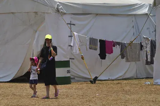 A Ukrainian refugee walks with her child at a camp in Utopia Park in Iztapalapa, Mexico City, Monday, May 2, 2022. (AP Photo/Marco Ugarte)