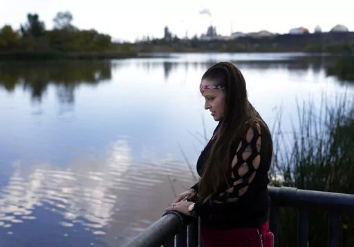 Moonlight Pulido stands by the shore at Harbor Lake Wednesday, Dec. 7, 2022, in Los Angeles. California is paying reparations to victims, mostly women, who were either forcibly or coercively sterilized by the government. Pulido was sterilized while incarcerated in 2005. (AP Photo/Marcio Jose Sanchez)