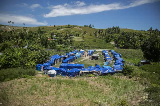 Blue tarps serve as roof coverings in Camp Devirel set up by earthquake refugees in Les Cayes, Haiti, Wednesday, Aug. 17, 2022. A year after a magnitude-7.2 quake hit southern Haiti, the hundreds that were left homeless are still living in the same makeshift tents. (AP Photo/Odelyn Joseph)