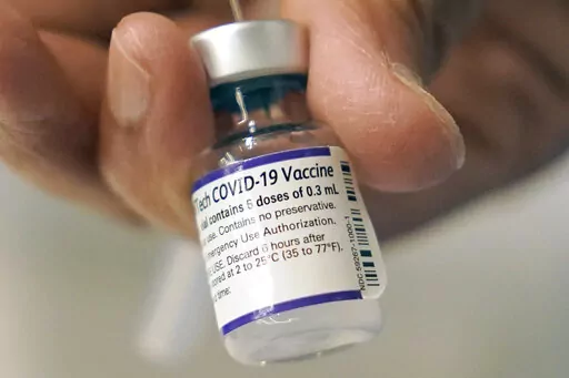 A doctor loads a dose of Pfizer COVID-19 vaccine into a syringe, Thursday, Dec. 2, 2021, at a mobile vaccination clinic in Worcester, Mass. In January 2022, an influential government advisory panel is considering COVID-19 boosters for younger teens, as the U.S. battles the omicron surge and schools struggle with how to restart classes amid the spike. (AP Photo/Steven Senne, File)