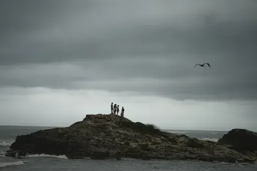 People stand on a rocky outcrop in the aftermath of Hurricane Beryl in Tulum, Mexico, July 5, 2024. (AP Photo/Fernando Llano, File)