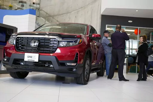 Customers confer with a salesperson as a 2022 Ridgeline pickup truck sits on the showroom floor of a Honda dealership, Friday, April 15, 2022, in Highlands Ranch, Colo. (AP Photo/David Zalubowski, File)