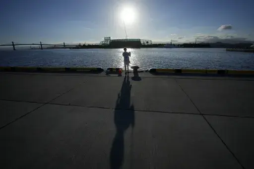 An angler fishes at Onahama Port in Iwaki, northeastern Japan, 68 kilometers (42 miles) from the Fukushima Daiichi nuclear power plant, damaged by a massive March 11, 2011, earthquake and tsunami, on Friday, Aug. 25, 2023. Fish auction prices at a port south of the Fukushima Daiichi nuclear power plant Friday somehow dipped amid uncertainty about how consumers may respond a day after release to sea of treated and diluted radioactive wastewater began despite protests at home and in neighboring co
