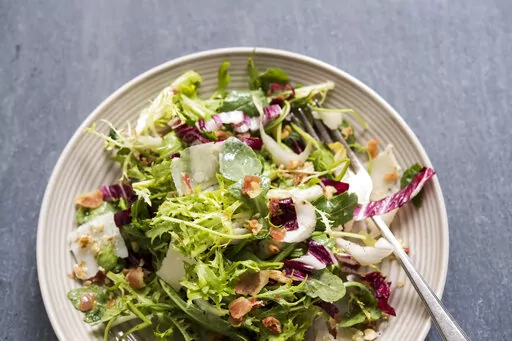 This image released by Milk Street shows a recipe for greens with walnuts, parmesan and pancetta vin. (Milk Street via AP)