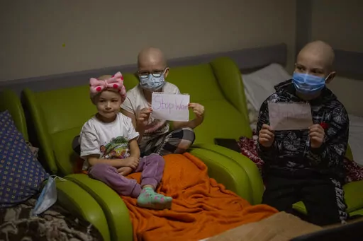 Oncology patients hold up sheets of paper with the words "Stop War" in a basement used as a bomb shelter at the Okhmadet children's hospital in central Kyiv, Ukraine, Monday, Feb. 28, 2022. (AP Photo/Emilio Morenatti)