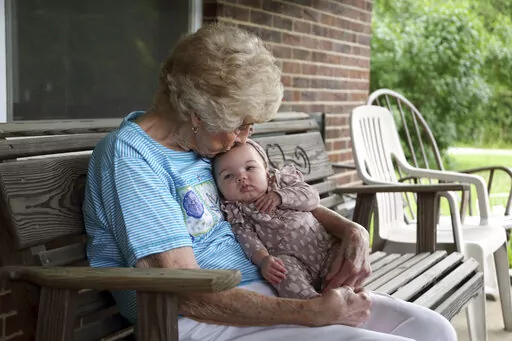 Tressie Corsi sits with her great great granddaughter Amelia Hollis on the porch of the house she has owned in Johnstown, Ohio, since 1972 to that she is giving up to make way for an Intel manufacturing plant during an interview Monday, June 20, 2022. Corsi and her husband raised four children and welcomed multiple generations of grandchildren and great-grandchildren, including some who lived right next door. (AP Photo/Paul Vernon)